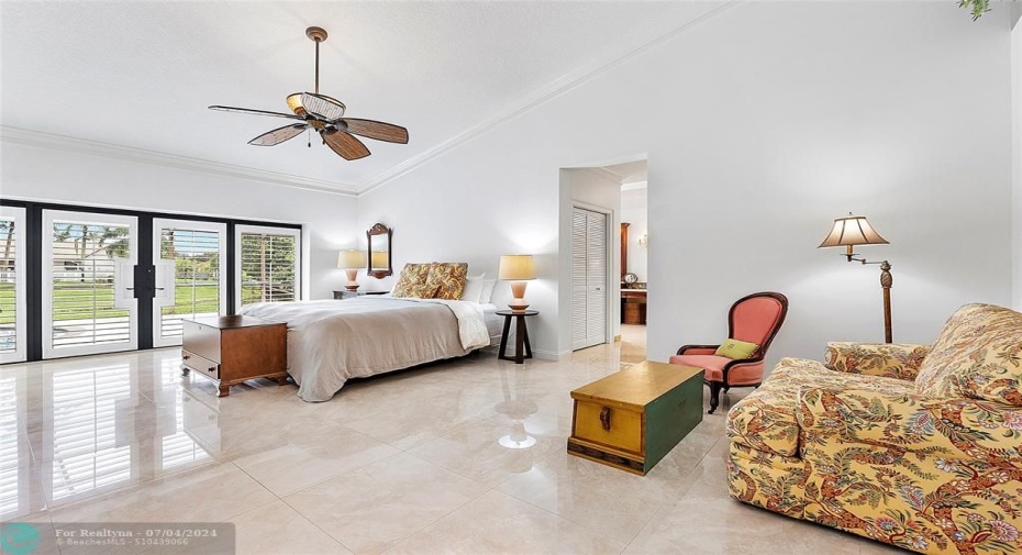 Large Primary Suite offering: seating area, plantation shutters, water views, multiple closets, and luxurious ensuite bathroom.