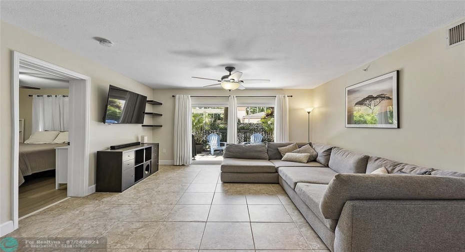 Open floorplan family room with Italian tile flooring, looking out onto the private serene garden patio area, perfect for BBQuing and relaxing, just add a few flowers,