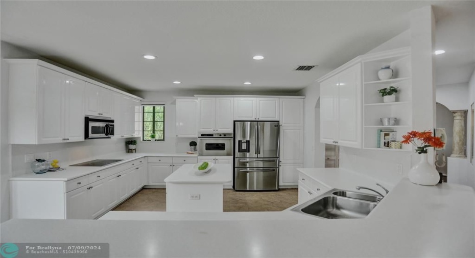 Sleek white cabinetry with crown molding, stainless appliances, display niche, stainless appliances and white corion countertops, create a timeless appeal.