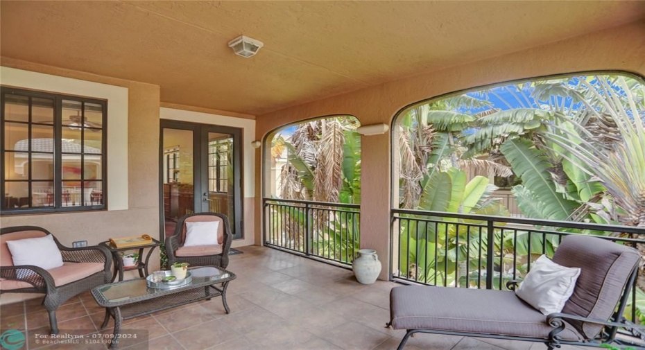Generous covered tiled patio, surrounded by lush landscaping, creating a private oasis.