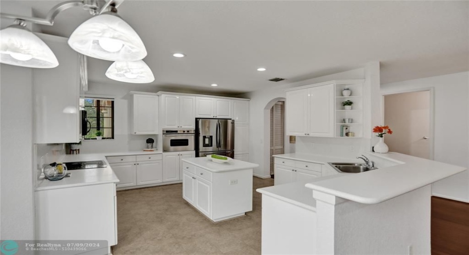 Huge crisp kitchen, stainless steel appliances, sleek white cabinetry with tons of storage, center island.
