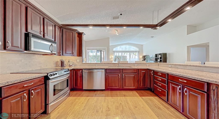 Large working Kitchen opens to family room w vaulted ceiling and views of the tropical backyard!