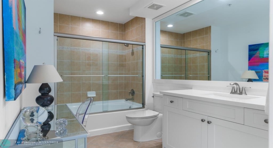 Spacious guest bath with tub/shower combo, modern white cabinets and quartz countertops