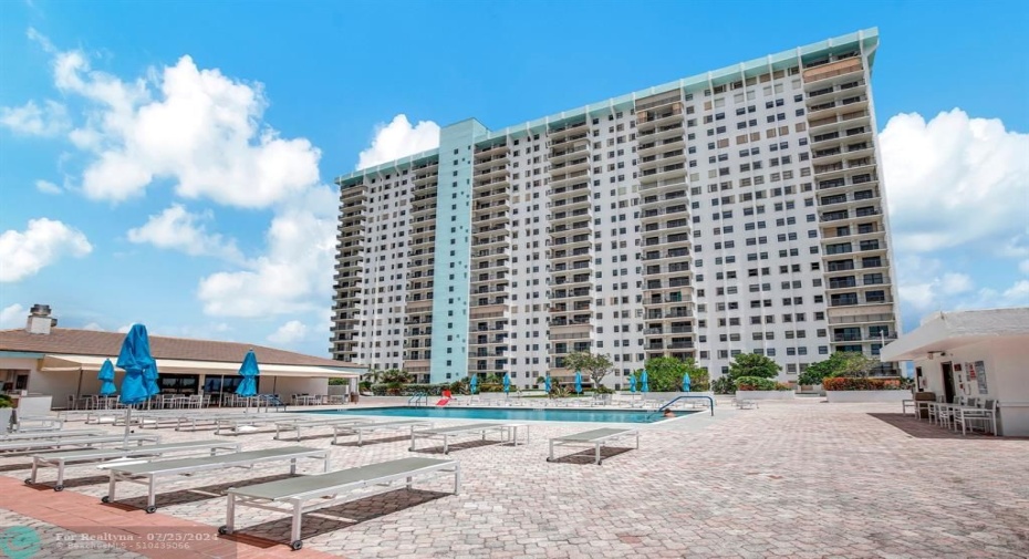 Enormous pool deck that overlooks both the ocean and the intracoastal with two heated pools, loungers, umbrellas and onsite restaurant in the center.