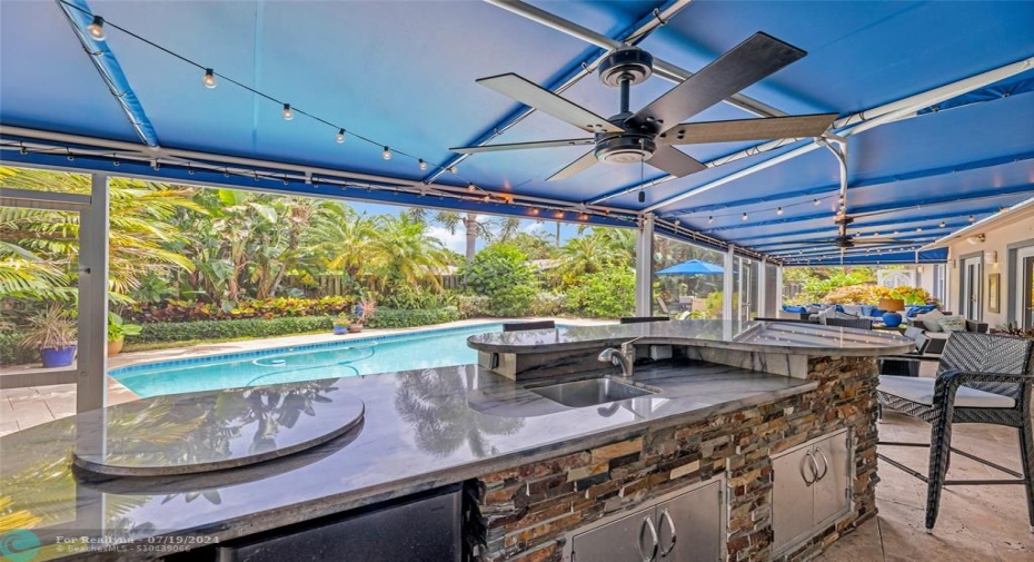 Outdoor Kitchen and Bar in Screened Room with a view of the pool