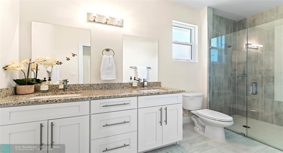 Double vanities & large shower with penny tile floor and accent wall