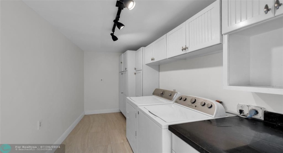 Large indoor laundry room with an abundance of storage