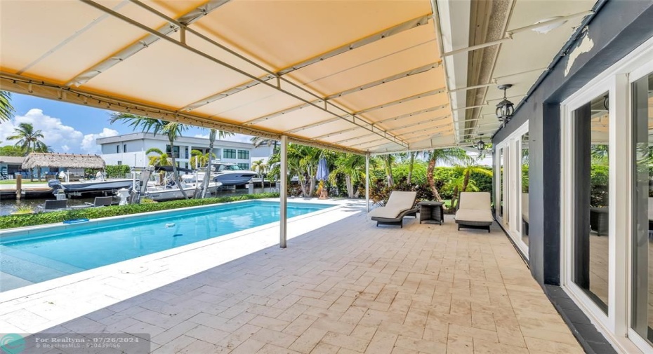 Large covered travertine patio and updated pool area on the water is perfect space to relax and entertain