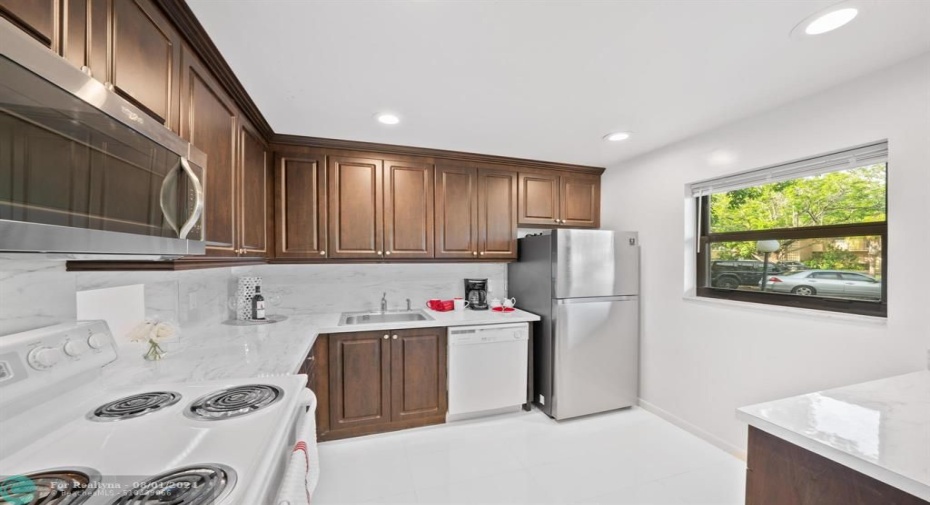 The 10' x 9' kitchen features a Samsung SS refrigerator, window for natural sunlight and snack bar/storage/pantry.