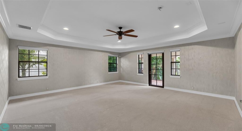 Large master bedroom with custom raised ceilings and French door to front balcony