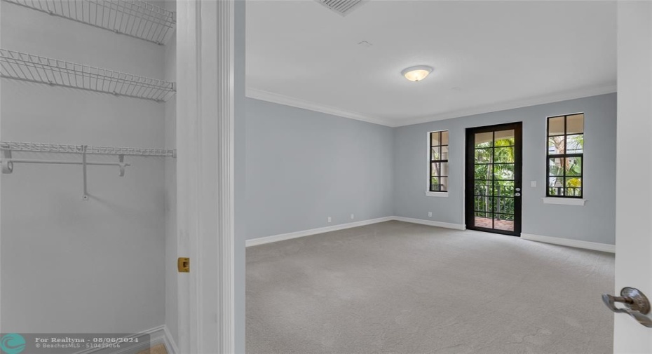 Third bedroom with French door out to balcony overlooking pool and backyard and extra storage closet