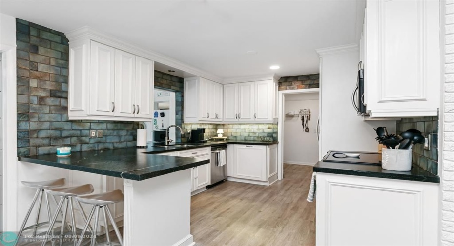 Updated kitchen with Brazilian stone countertops, tile backsplash, SS appl, white cabinets with under lighting.