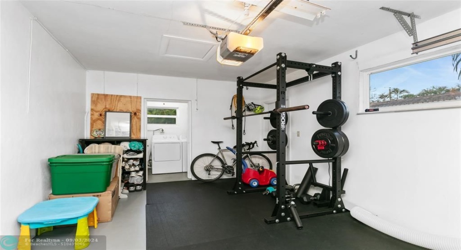 Garage with laundry room in background and impact large door, side door & window. What a great space for your car or as it is set up for a great workout or whatever you envision.