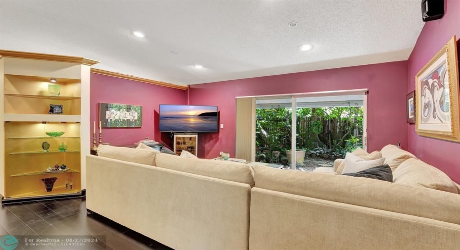 The living room, with lighted display niche, crown molding & rich bamboo flooring, has impact glass sliding doors that open to an aluminum covered porch & fenced garden retreat, with exotic plants abound!