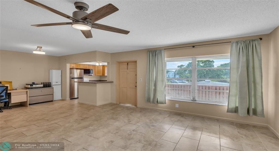 Tile flooring and ceiling fan with overhead lighting offered in living room / dining room