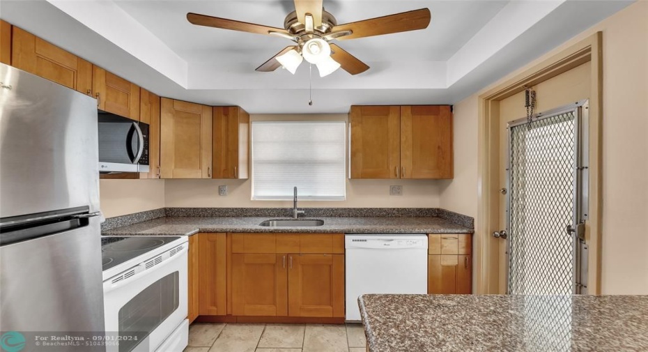 Kitchen with wood cabinets and convenient entry door is great for grocery shopping