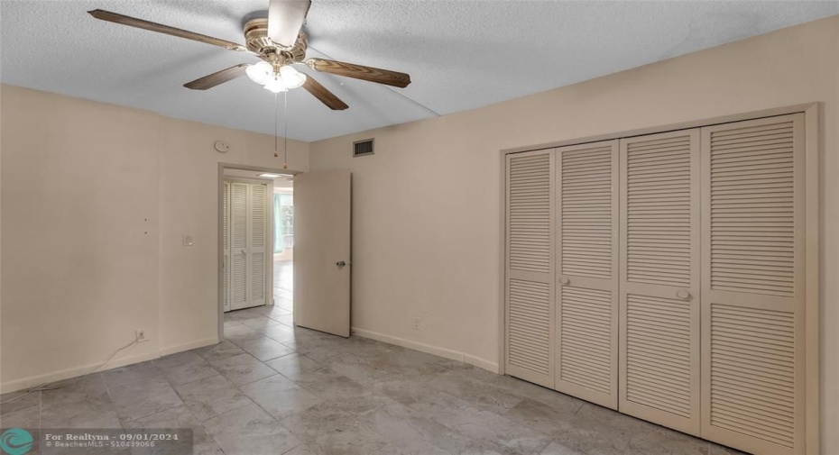 Second bedroom offers wall of closets and overhead ceiling fan with lighting