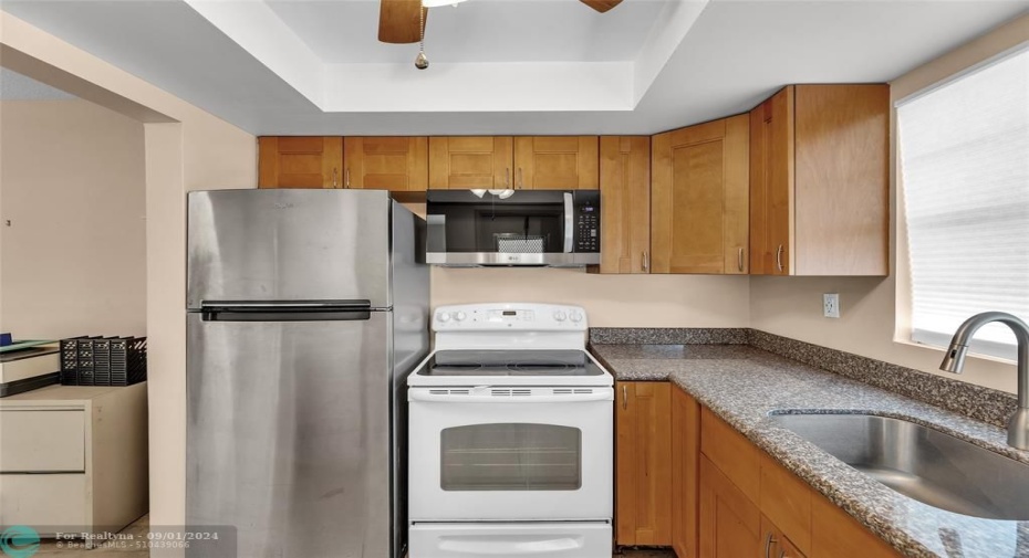 Kitchen with woof cabinets and fan with overhead lighting and window for additional natural light