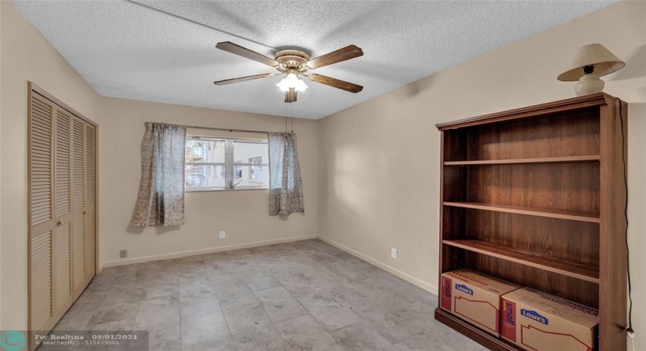 Second bedroom features wall of closets, tile flooring, ceiling fan with lighting and great natural light