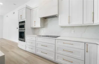 Stunning designer kitchen with Quartz range hood and KitchenAid appliances.