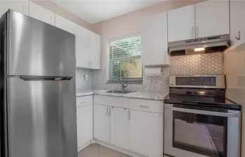 Bright kitchen with modern backsplash and SS appliances.