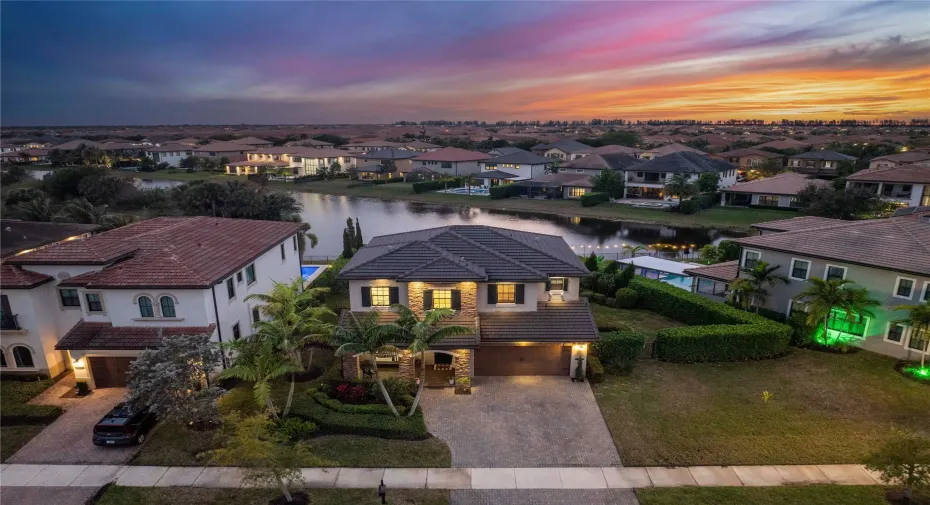 The front aerial nightime view of this spectaular home with the lake flowing behind & breathtaking sunsets