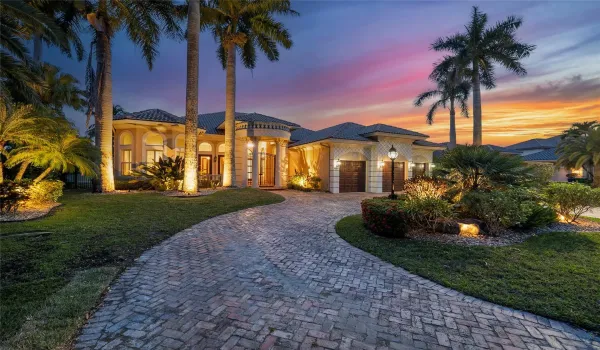 A nighttime view of the custom built home with new landscape lighting, A circular driveway that is paved with Chicago brick and can hold at least 9 cars and additional 3 cars inside the garage.