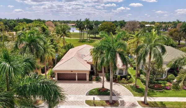 Wide brick paver circular driveway, tall palms, manicured landscaping creates beautiful curb appeal.