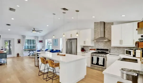 Open concept kitchen with a quartz countertop island. Stainless steel appliances.