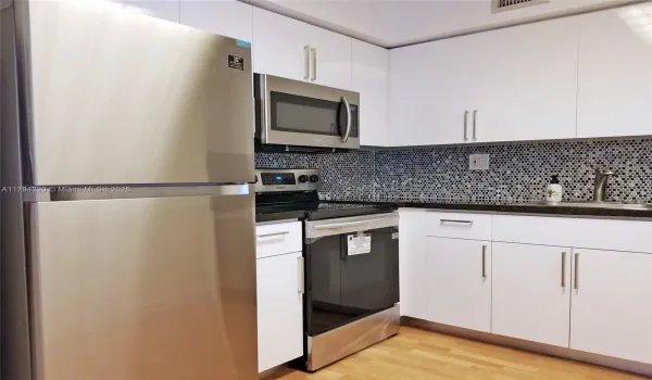 New kitchen with new stainless steel appliances and glass tile backsplash.